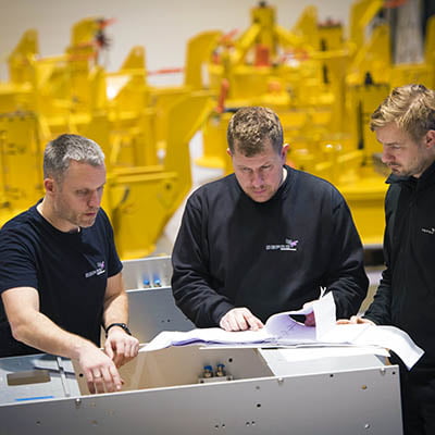 Three men discussing solutions in Depro's workshop.