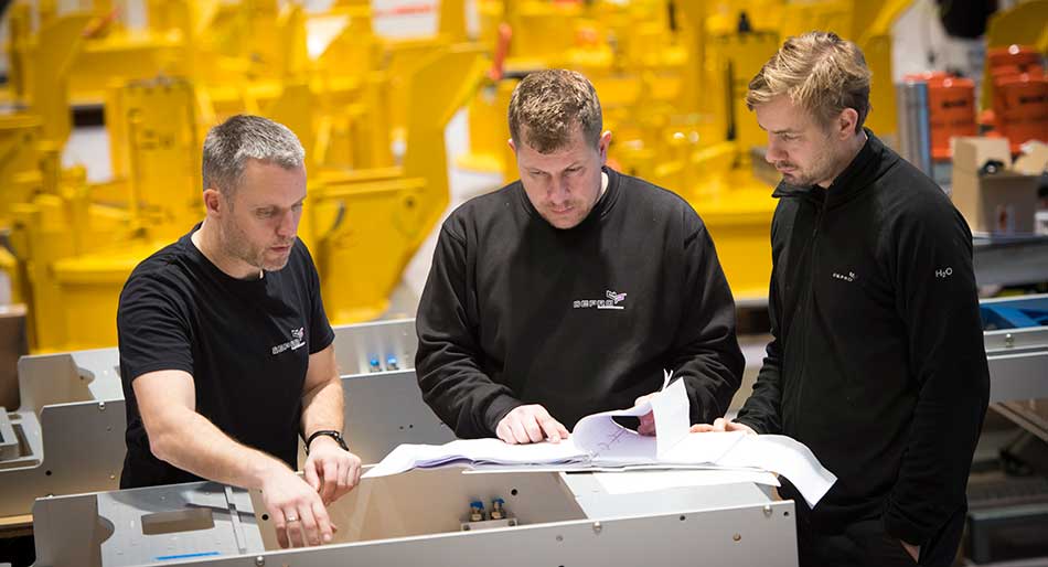 Three men discussing solutions in Depro's workshop.